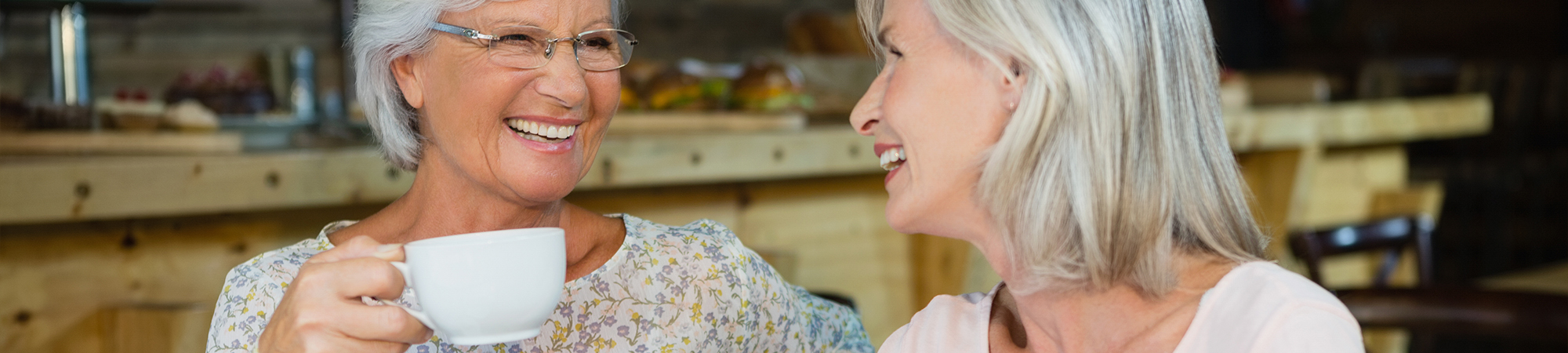 Two smiling older women share a joyful moment